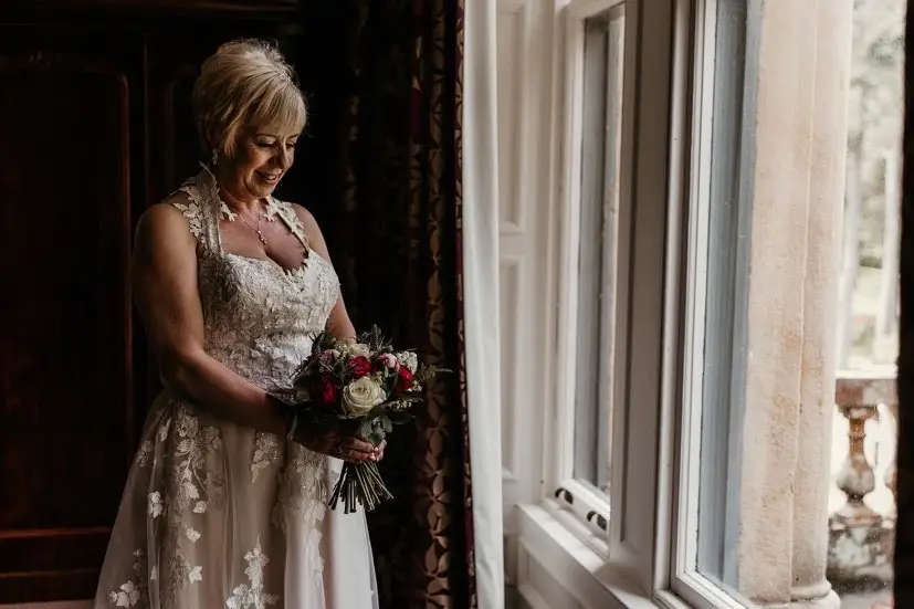 Bride holding a bouquet by a window