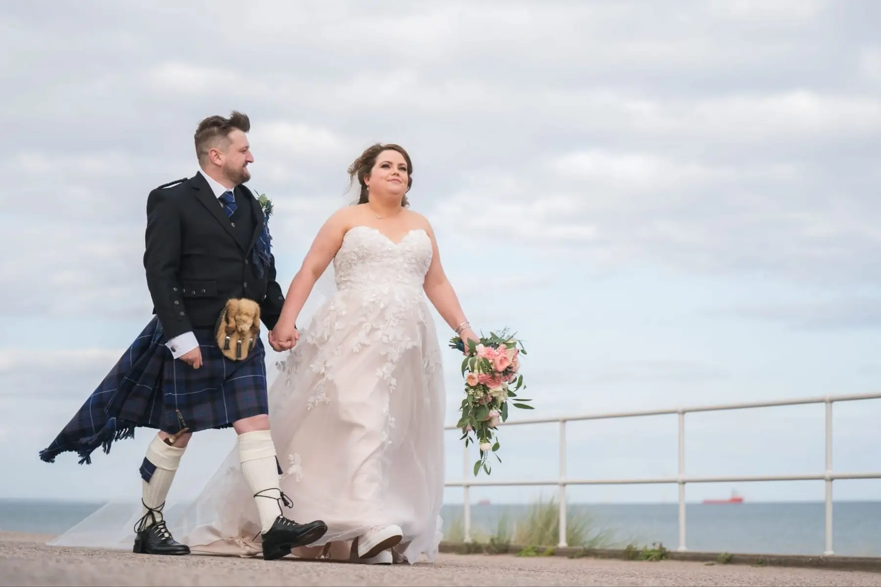 Newlyweds walking beside the coast